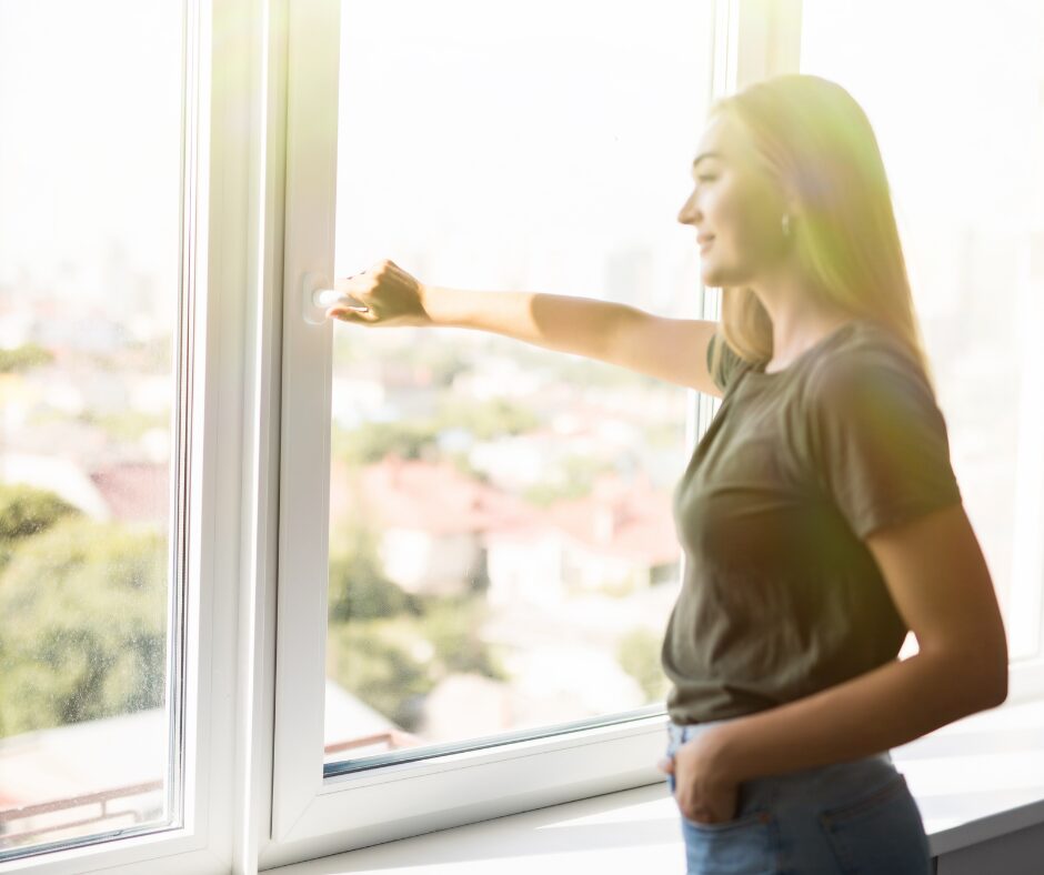 Woman standing by a window breathing fresh air.