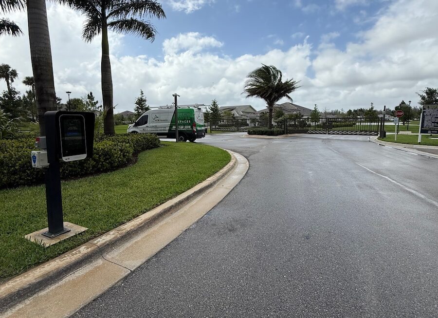 Gated residential entrance with an ATI Systems van stopped at a gate, monitored by surveillance cameras and access control system.